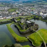 Aerial shot of a castle surrounded by a moat and green embankment.