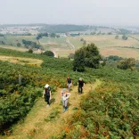 Group of walkers on a mountain footpath with scenic views beyond.