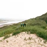 Group of ladies walking along sand dunes toward the beach.