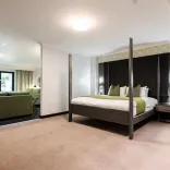 An executive bedroom in a hotel with a lounge and sliding doors to a terrace.