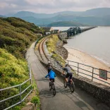 People riding bikes down a bridge.
