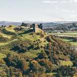 A castle on a hill with views alongside a river surrounded by countryside.