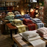 Woven blankets and cushions on display in a shop.