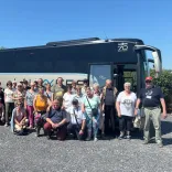 Group of people standing by a coach smiling at the camera