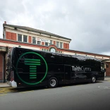A coach parked up outside a train station.