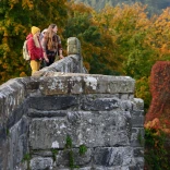 A small group of people on a bridge by Tu Hwnt I'r Bont in autumn.
