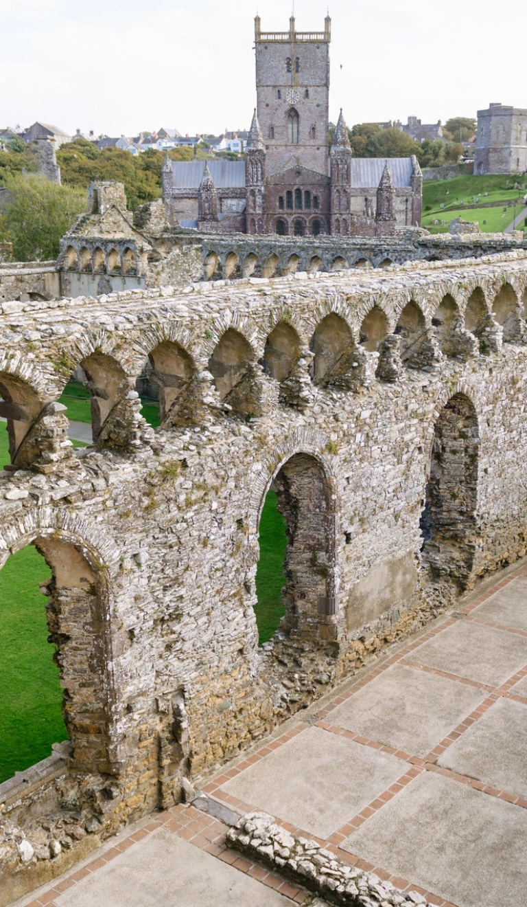 Ruins of a bishop's palace with a cathedral in the background.