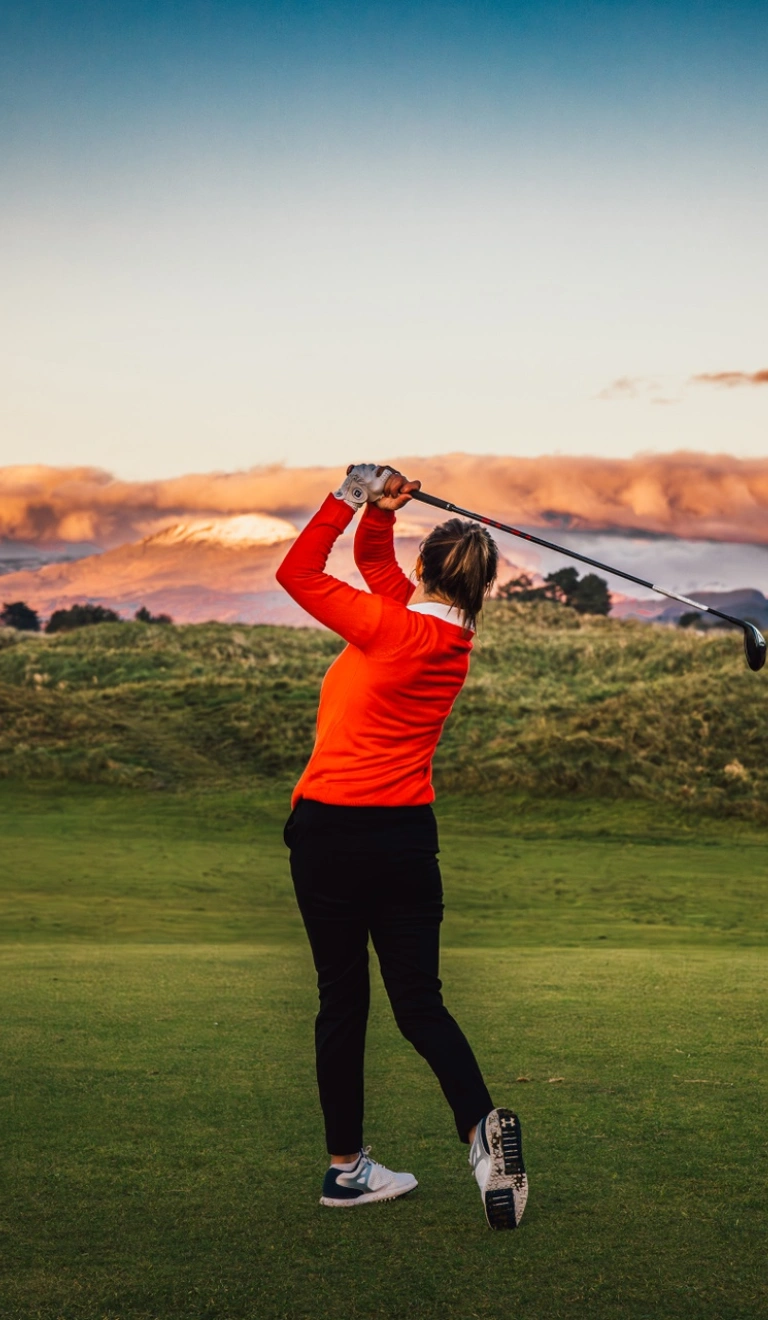 A golfer taking a shot with a castle in the foreground.