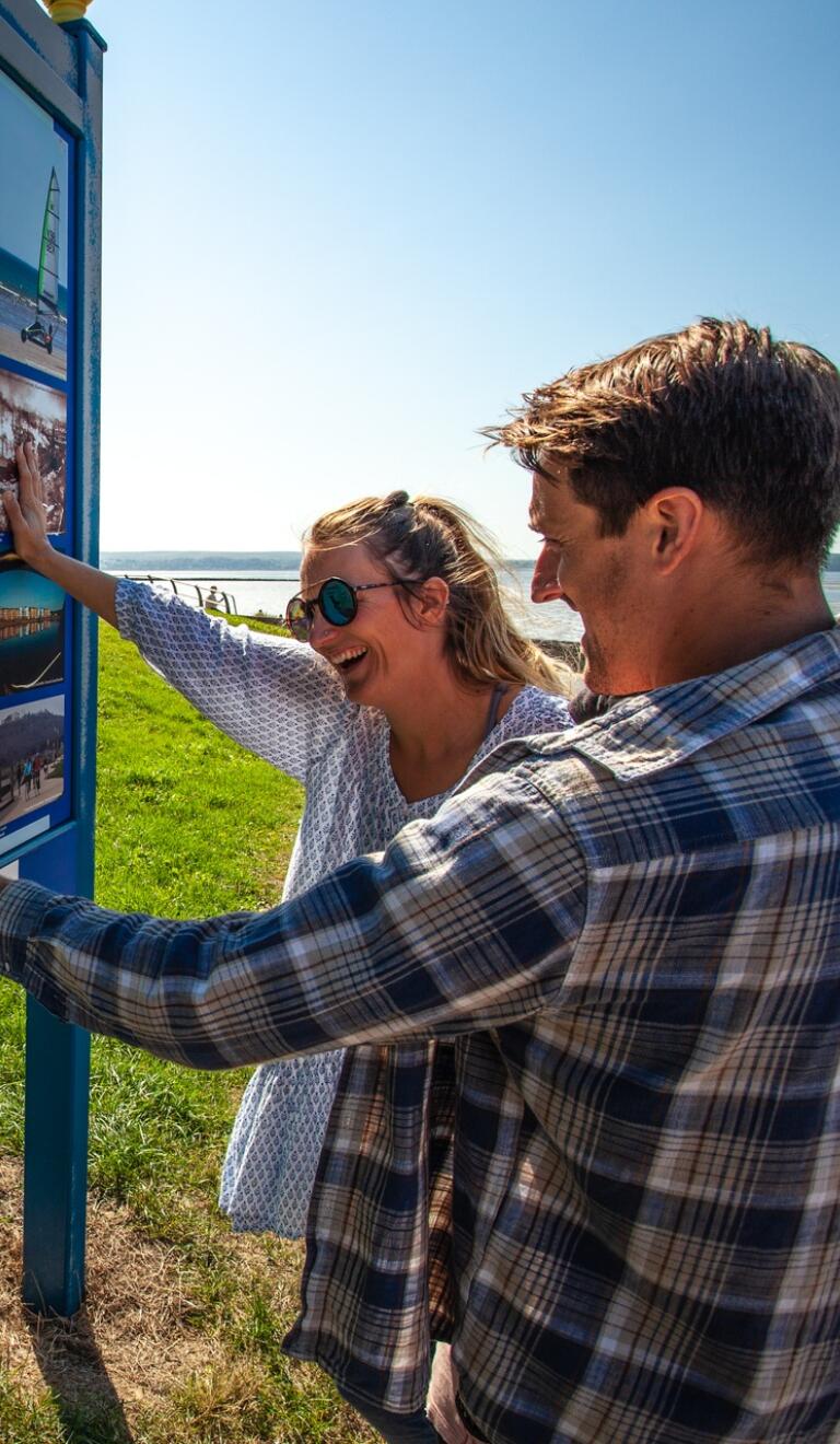 Couple looking at a tourism information sign for the Wales Coastal Path.