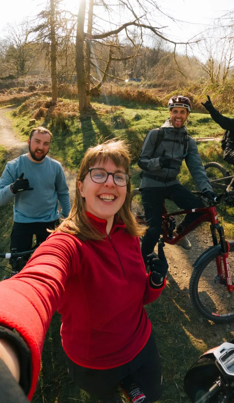 Group of people with their bikes in a bike park smiling at the camera.