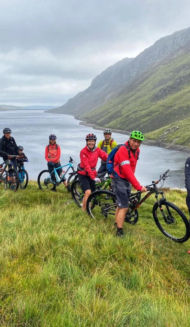 Group of cyclists surrounded by a lake and mountains.