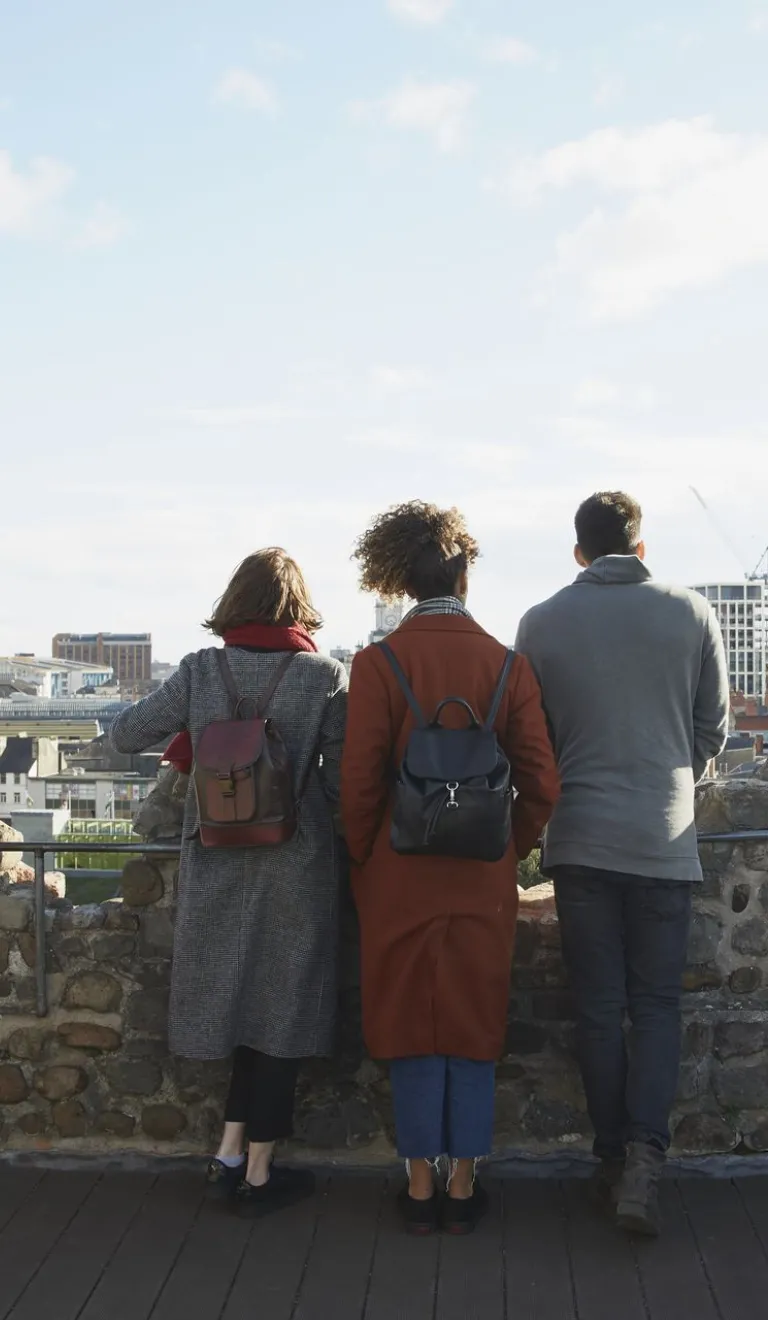 Group of people on a castle turret looking out towards the city.